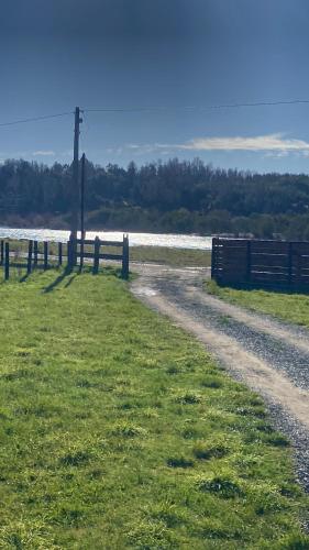 a dirt road with a fence next to a field at El Encanto de Antilhue in Valdivia