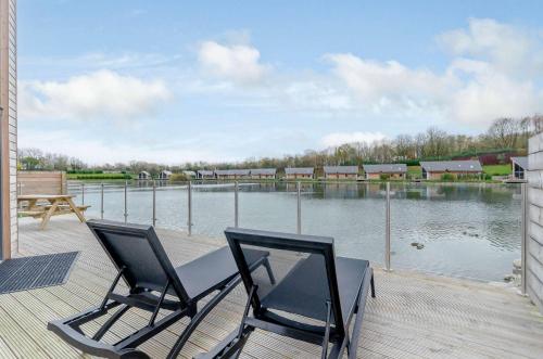 two chairs on a deck with a view of a lake at Landal Twin Lakes in Carnforth
