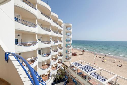 a view of the beach from the balcony of a hotel at Hotel Playa Victoria in Cádiz