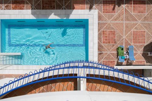 a person swimming in a swimming pool on a bridge at Hotel Playa Victoria in Cádiz