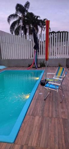 an umbrella and two chairs next to a swimming pool at Kitnet privada confortável em Pontal do Sul in Pontal do Paraná
