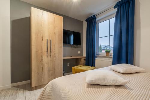 a bedroom with a bed and a cabinet with a television at Jaskółka - pokoje i apartament przy plaży in Olsztyn