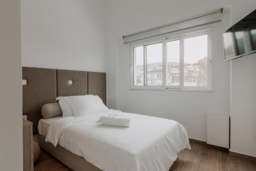 a bedroom with a large white bed with a window at Neutral Haven in Nafplio