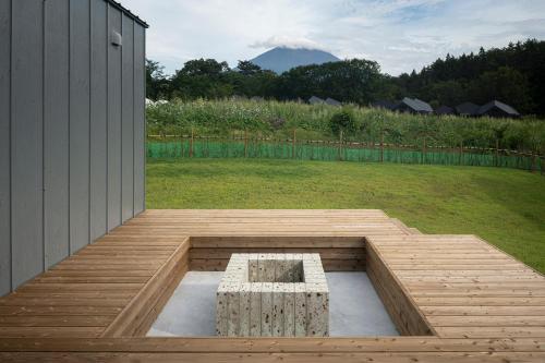 a wooden deck with a bench in a yard at グランピングヴィレッジ富士河口湖 in Narusawa