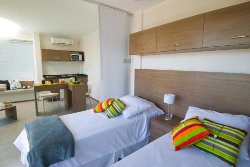 カンパーナにあるRefugio Urbano Apartamentosのベッド2台とキッチン付きのホテルの部屋