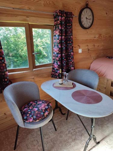 une chambre avec une table, deux chaises et une horloge dans l'établissement l'Eden du Sancerrois, à Sens-Beaujeu