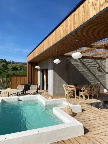 une maison avec une piscine et une terrasse en bois dans l'établissement Magnifique villa écologique piscine jacuzzi, à Clarensac