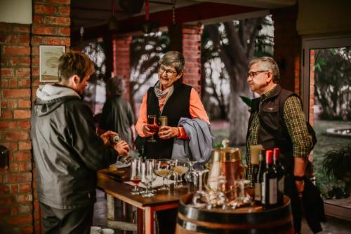 a group of three men standing around a bar with wine glasses at Ouhave Country Home in Osire