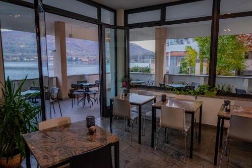 a restaurant with tables and chairs and large windows at Hotel Chalet del Lago in Avigliana