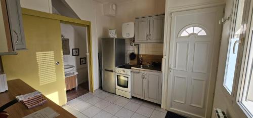 une cuisine avec une porte s'ouvrant sur une cuisine équipée d'un réfrigérateur. dans l'établissement Appartement F2 Orléans 42m2, parking, 4 couchages et lit bébé, à Orléans