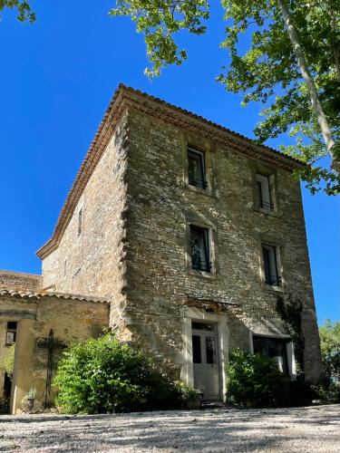 an old brick building with a blue sky in the background at Magnanerie de Sainte Croix in Saint-Hippolyte-de-Caton