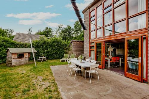 a patio with a table and chairs in a yard at Dutchen Vakantiepark Buiten Bergen in Schoorl