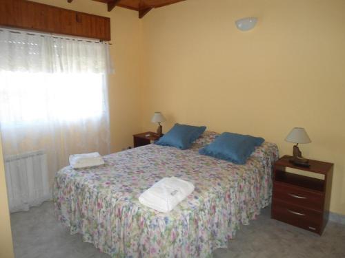 een slaapkamer met een bed met blauwe kussens en een raam bij Hosteria Luz de Luna in Valeria del Mar