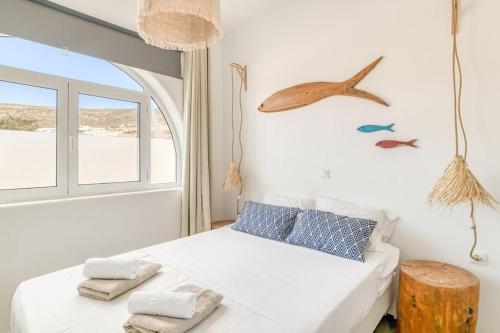 a bedroom with a bed with a window and a bird on the wall at Onikos House - South Gem in Kampos Paros