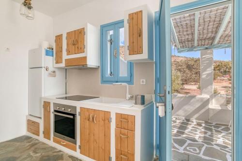a kitchen with wooden cabinets and a blue door at Onikos House - South Gem in Kampos Paros
