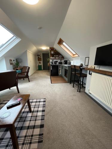 a living room with a couch and a tv in a attic at Modern 2-Bedroom Loft Apartment - Pendle Hill & Ribble Valley Views - Free Parking in Church