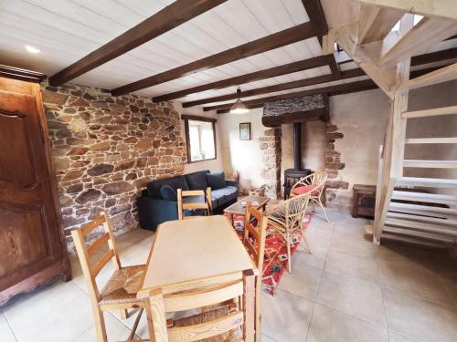 - un salon avec des tables et des chaises et un mur en pierre dans l'établissement Chestnut - Charming cottage - Renovated 2024- Gîte de charme - Rénové 2024, à Plougasnou
