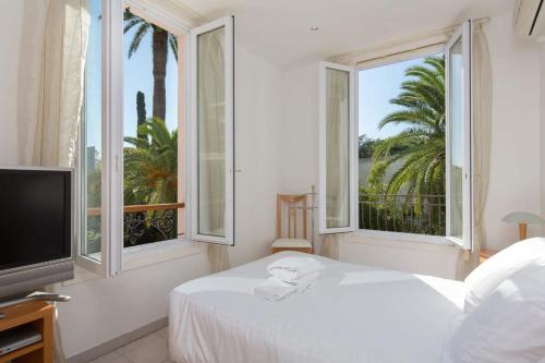 une chambre avec un lit, une télévision et des fenêtres dans l'établissement B024 - Magnifique Villa - Piscine - Cannes centre, à Cannes