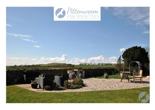 a garden with a table and chairs and a fence at Kittle View near Anstruther in Carnbee