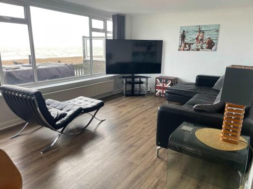 a living room with a couch and a flat screen tv at Luxury Beachfront The Cozy Clam in Pevensey