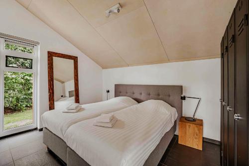 a bedroom with a large bed and a mirror at Dutchen Vakantiepark Buiten Bergen in Schoorl