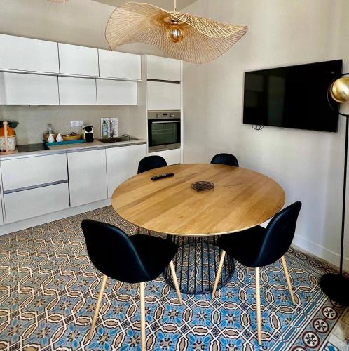une cuisine avec une table en bois et des chaises noires dans l'établissement Charming 2 Bedrooms & 1 sofa bed renovated 3P3, à Cannes