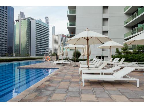 a pool with lounge chairs and umbrellas next to a building at Luxury 1-Bedroom Apartment with Pool, Gym & Balcony in Business Bay in Dubai