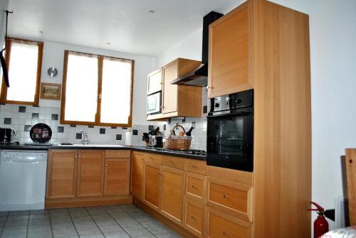 une cuisine avec des armoires en bois et un appareil noir dans l'établissement Les Gîtes Champêtres OAK Cottage, à Sainteny