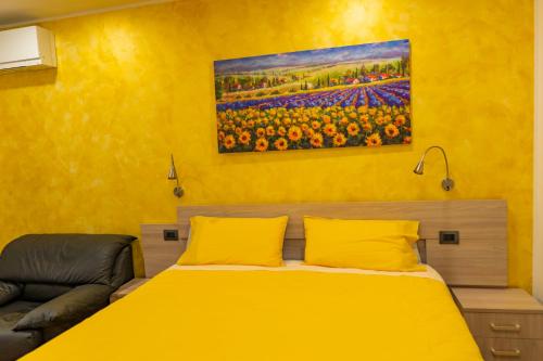 a yellow bedroom with a bed and a painting on the wall at Casa Fortuna in Monfalcone