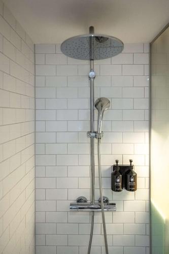 a shower in a bathroom with white tiles at pentahotel Liège in Liège