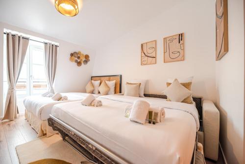 deux lits dans une chambre aux murs blancs dans l'établissement CIA - Champs Élysées Bright Studio 4P, à Paris