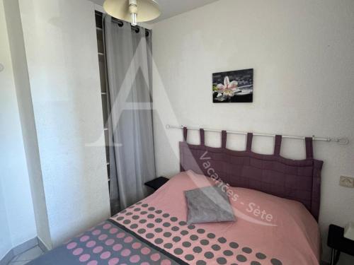 - une petite chambre avec un lit rose dans l'établissement LA PLAGE AU BOUT DE LA RUE, à Sète
