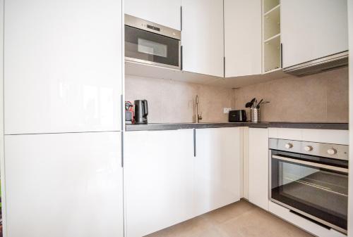 une cuisine blanche avec des armoires blanches et un micro-ondes dans l'établissement CIA - Temple Charming & Comfy Flat in Marias Paris, à Paris