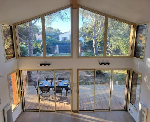 Elle offre une vue sur une salle à manger dotée de grandes fenêtres. dans l'établissement Villa Lou Pantaï la tranquillité à 2 pas de la mer, à Saint-Aygulf