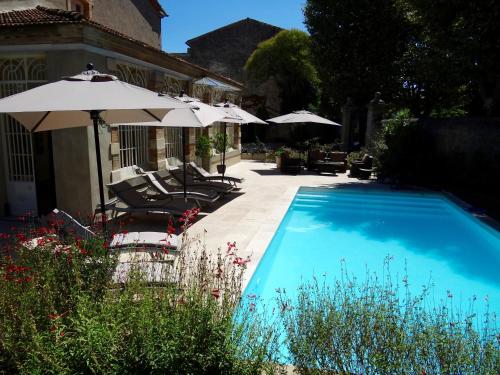 una piscina con sillas y sombrillas junto a una casa en Bed & Breakfast L'Orangerie, en Carcassonne