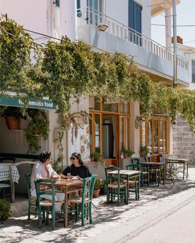 two women sitting at a table outside a restaurant at Phāea Blue - Small Luxury Hotels of the World in Elounda