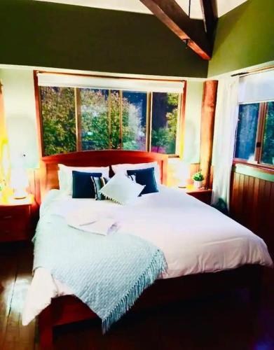 a bedroom with a large white bed with two windows at Pemberton Forest View Retreat in Pemberton