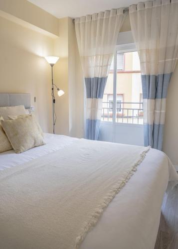 a bedroom with a white bed and a window at Apartamento cerca del Pilar in Zaragoza