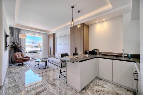 une cuisine avec des armoires blanches et un salon dans l'établissement Luxury Superbe Studio Miramar Croisette, à Cannes