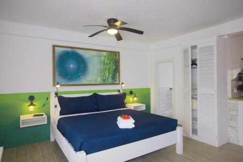 a bedroom with a blue bed and a ceiling fan at Treetops Hotel in Caye Caulker