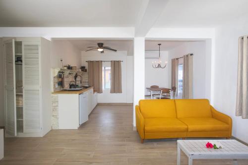 a living room with a yellow couch and a kitchen at Treetops Hotel in Caye Caulker