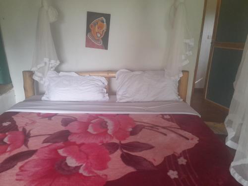 a bed with a pink flower blanket on it at Entale Safari Camp Queen Elizabeth National Park in Kasese