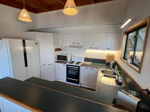 eine Küche mit weißen Schränken und einer schwarzen Arbeitsplatte in der Unterkunft Lakeview Treehouse at Queenstown Hill in Queenstown