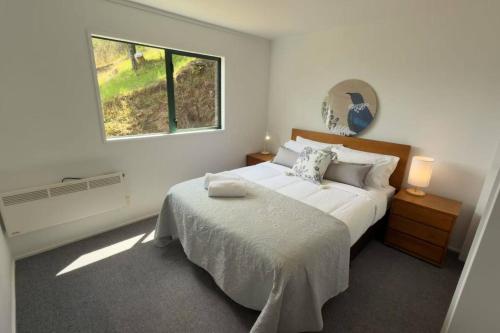 ein Schlafzimmer mit einem großen Bett und einem Fenster in der Unterkunft Lakeview Treehouse at Queenstown Hill in Queenstown