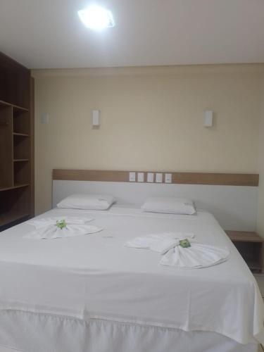 a bedroom with a white bed with two white pillows at Hotel Recanto Vip in Araripina