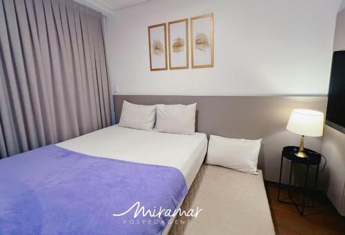 a bedroom with a large bed with a purple blanket at Move - Tambaú in Tambaú
