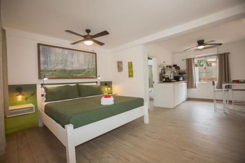 a bedroom with a bed with a green bedspread at Treetops Hotel in Caye Caulker