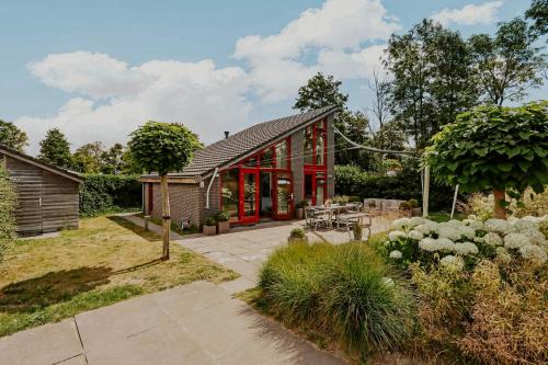 a house with red doors and a garden at Dutchen Vakantiepark Buiten Bergen in Schoorl