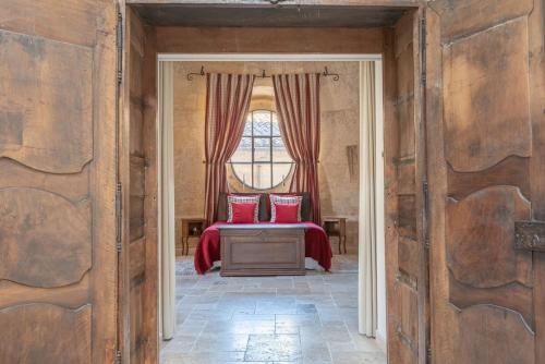 Cette chambre comprend un lit avec des oreillers rouges et une fenêtre. dans l'établissement Dormir dans une église du 13ème siècle au coeur d'Avignon, à Avignon