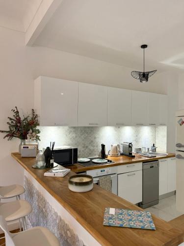 une cuisine avec des armoires blanches et un comptoir en bois dans l'établissement Appartement niçois au coeur du triangle d'or, à Nice